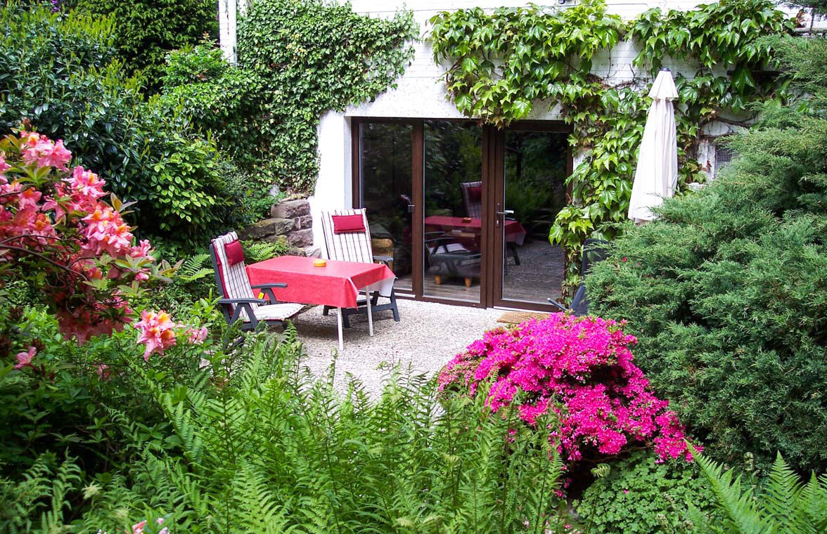 Terrasse der Ferienwohnung mit Gartenmöbeln und blühendem Rhododendron